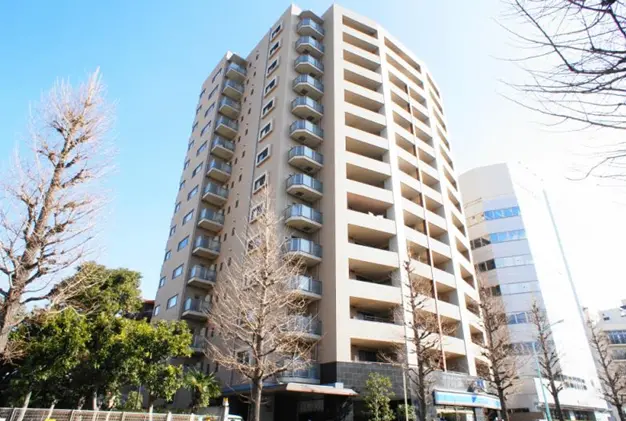- モダンな外観の地上10階建てマンション、周囲の木々と晴天の下で立つ建物