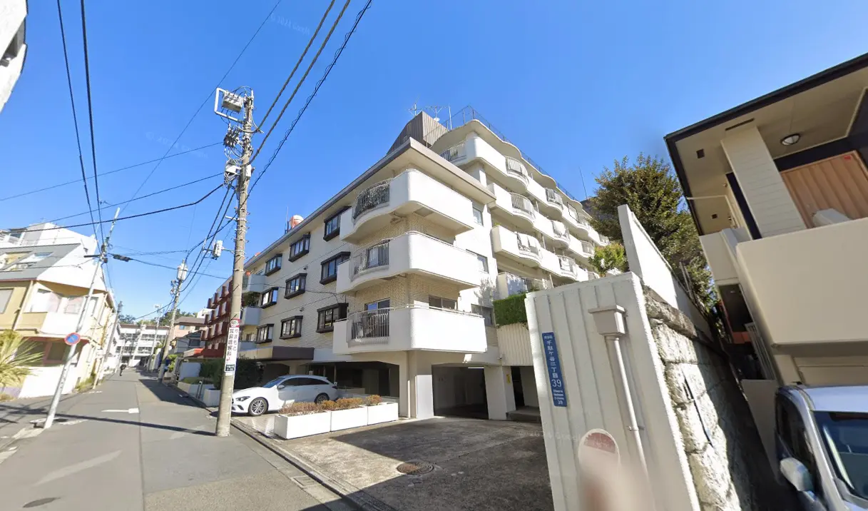 現代的なデザインのマンション外観、白い壁とバルコニー、晴れた日の青空と都市風景