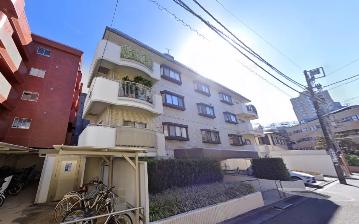 日本の都市部にあるマンションの外観、暖かい日差しと駐輪場と駐車場が見える外壁デザイン