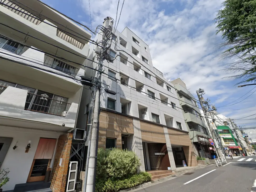 都市部に立つモダンなマンションの外観、電柱と交通信号機が見える通り沿い