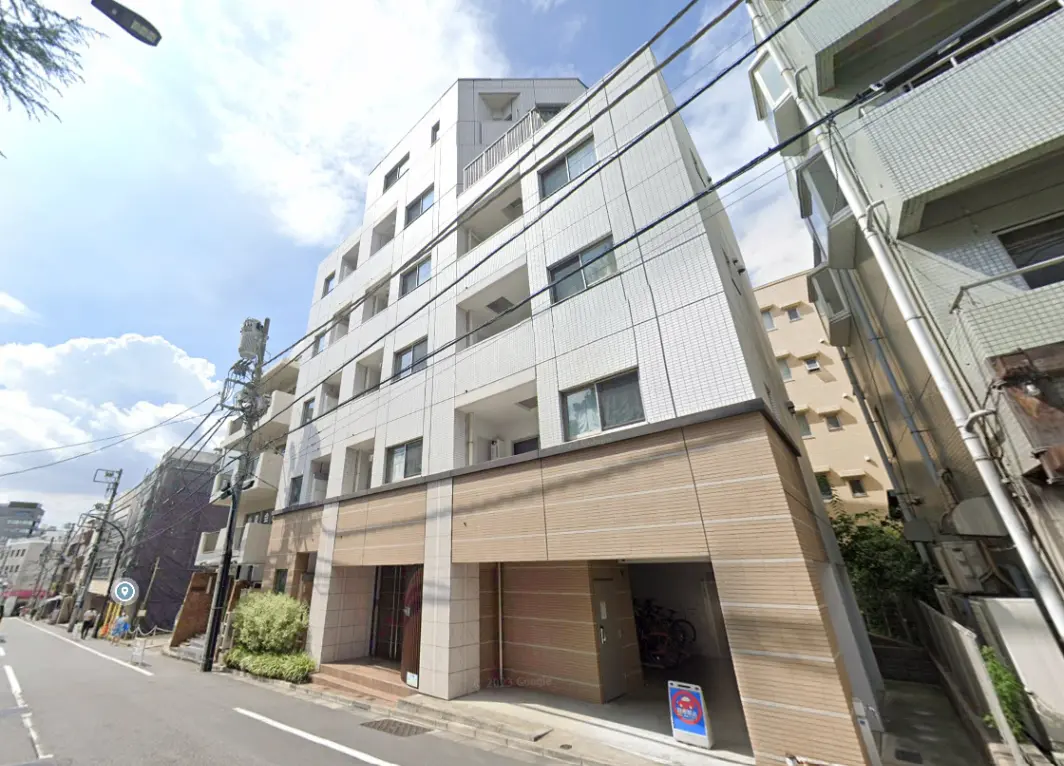 現代的なマンションの外観、白いタイルの壁と木目調のエントランス、都市の住宅街に位置する