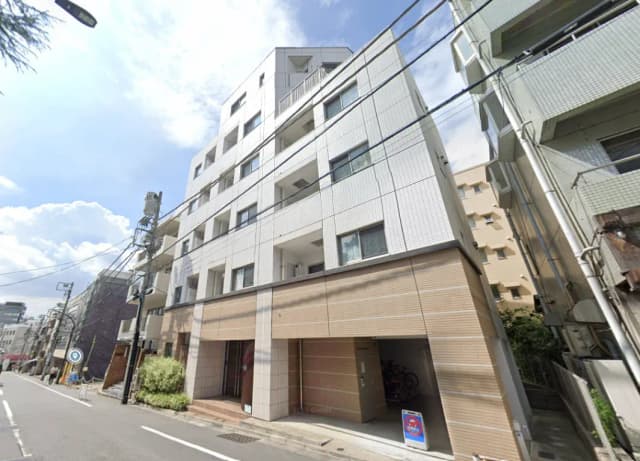 現代的なマンションの外観、白いタイルの壁と木目調のエントランス、都市の住宅街に位置する