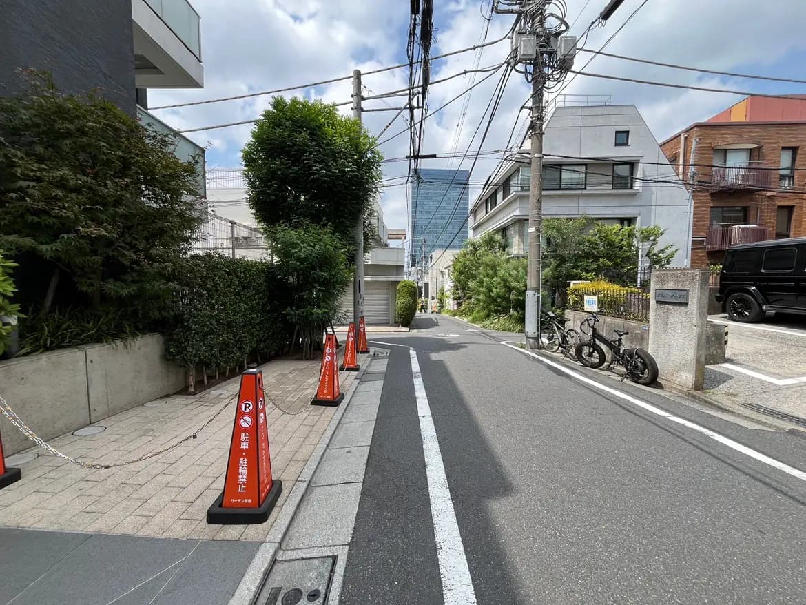- 都市の一角、舗装された道路と植物に囲まれた歩道、駐車禁止の警告ボードが並ぶ風景