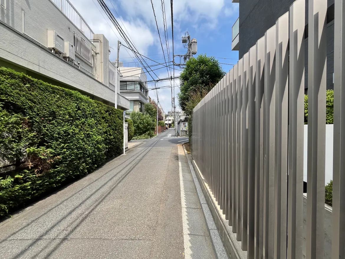 - 植栽に囲まれた静かな道路、近代的なフェンスと住宅が並ぶ都市の風景