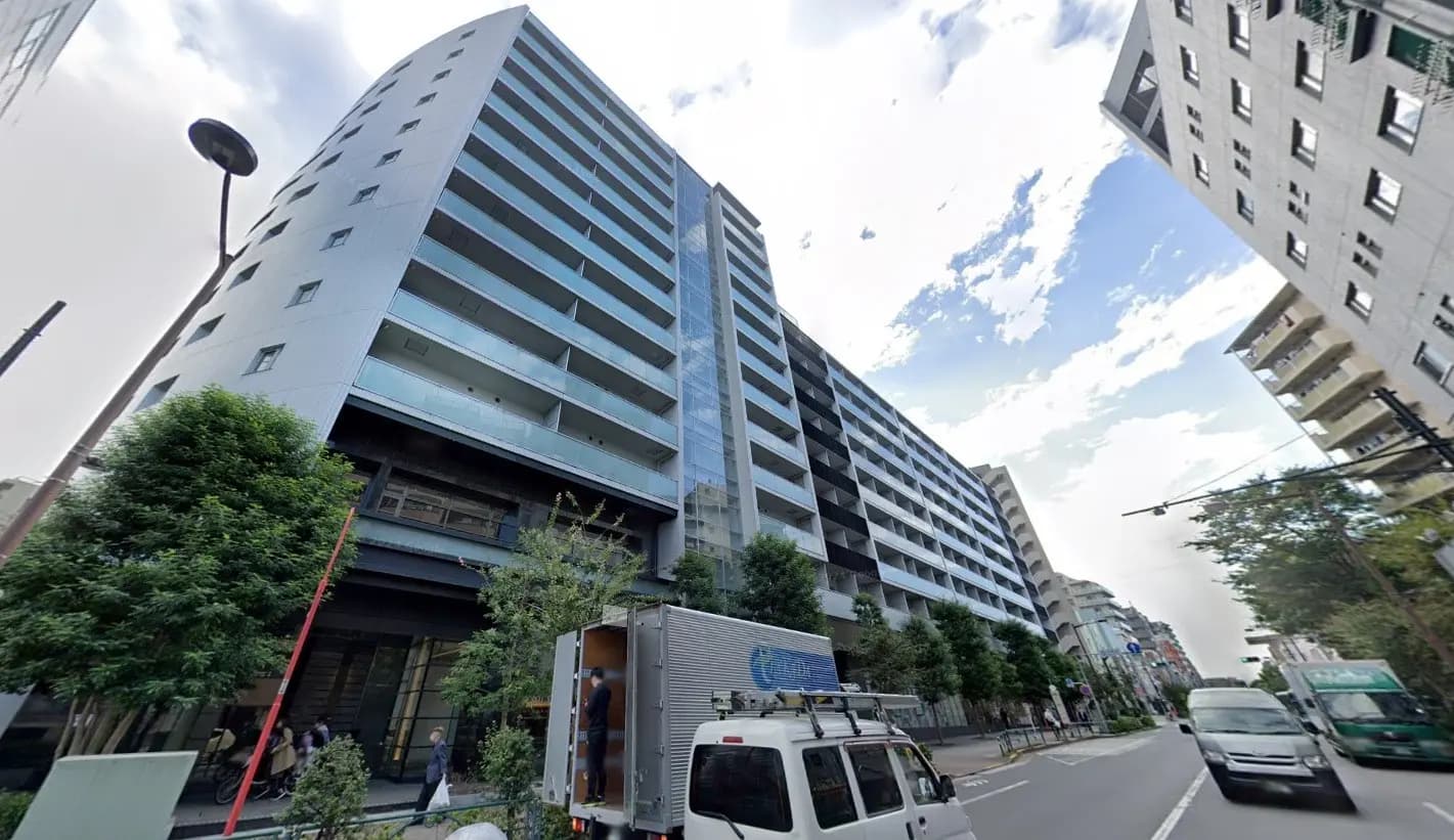 都市部に位置するモダンなデザインのマンションビル、周囲に緑がある景観
