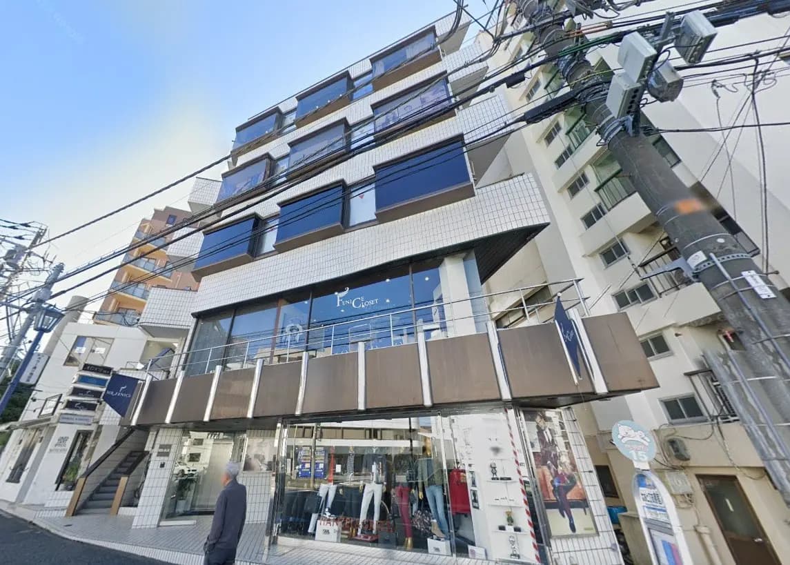 都市の通りに面したモダンな外観のビル、1階にはファッションブティックが入居