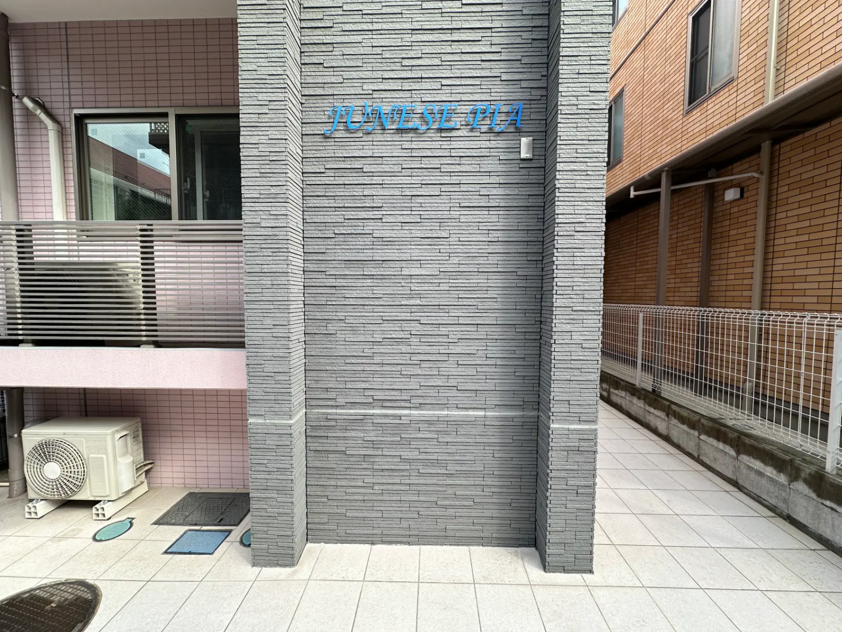 日本のアパートの外観、グレーの煉瓦壁、バルコニーとエアコンのユニット