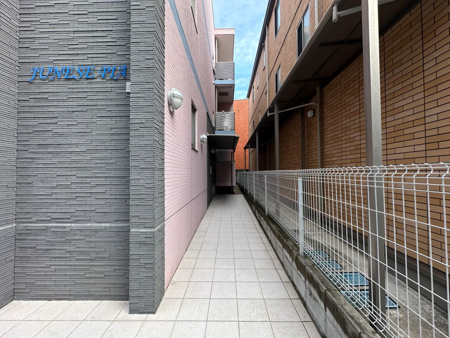 狭い通路とアパートの外観、灰色と茶色の壁、手すりのあるウォークウェイ