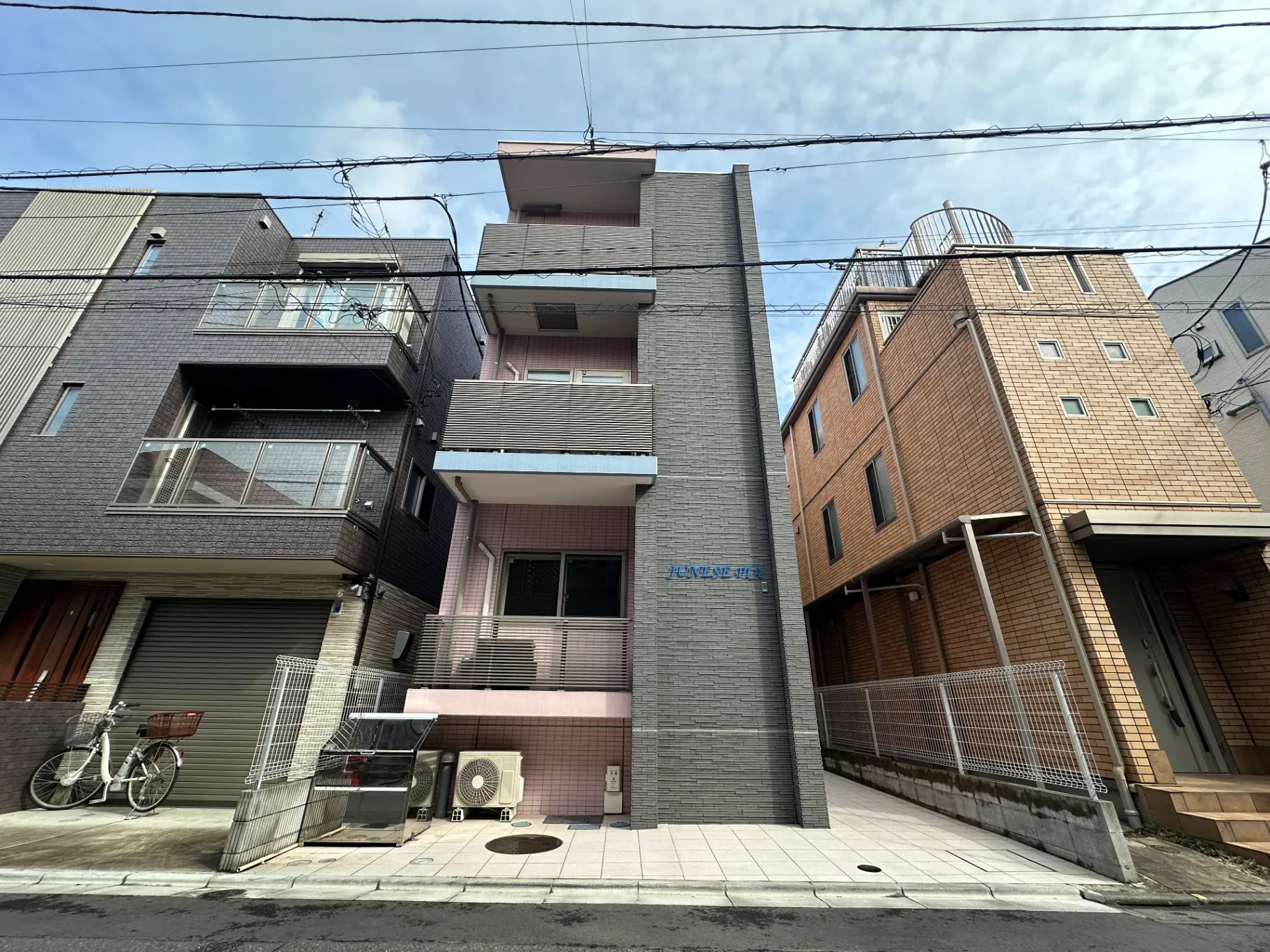 都市部に建つ現代的なデザインのアパートメントビル、電線が交差する街路景観