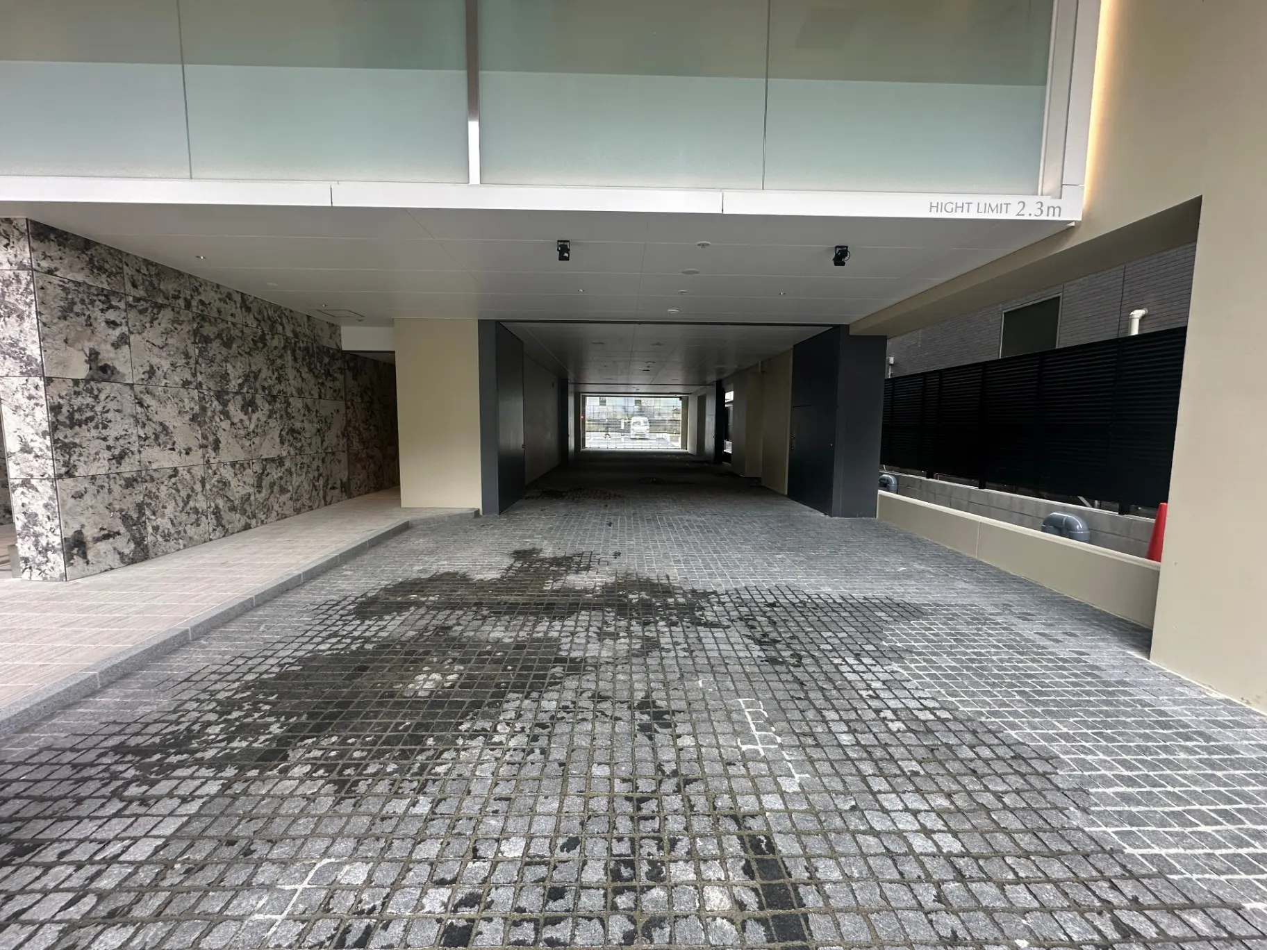 モダンな商業ビルの地下駐車場、コンクリートの壁と床、天井には明るい照明が設置されている