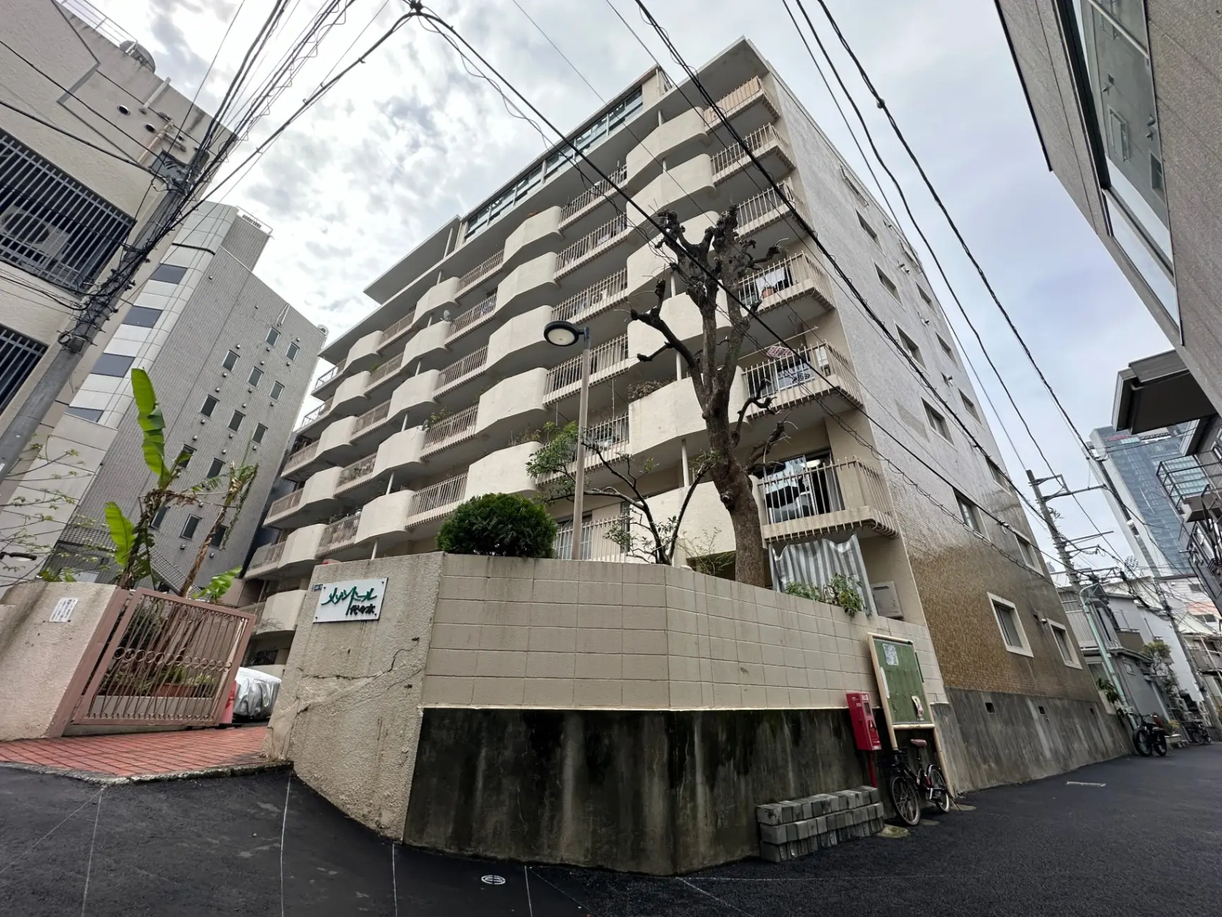 都市部に位置する現代的なマンションの外観、歩道と電信柱が見える景色