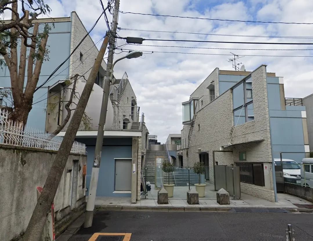現代的なデザインの都市型住宅、外観はレンガ調の壁と大きな窓、街路樹と電信柱が立ち並ぶ通り
