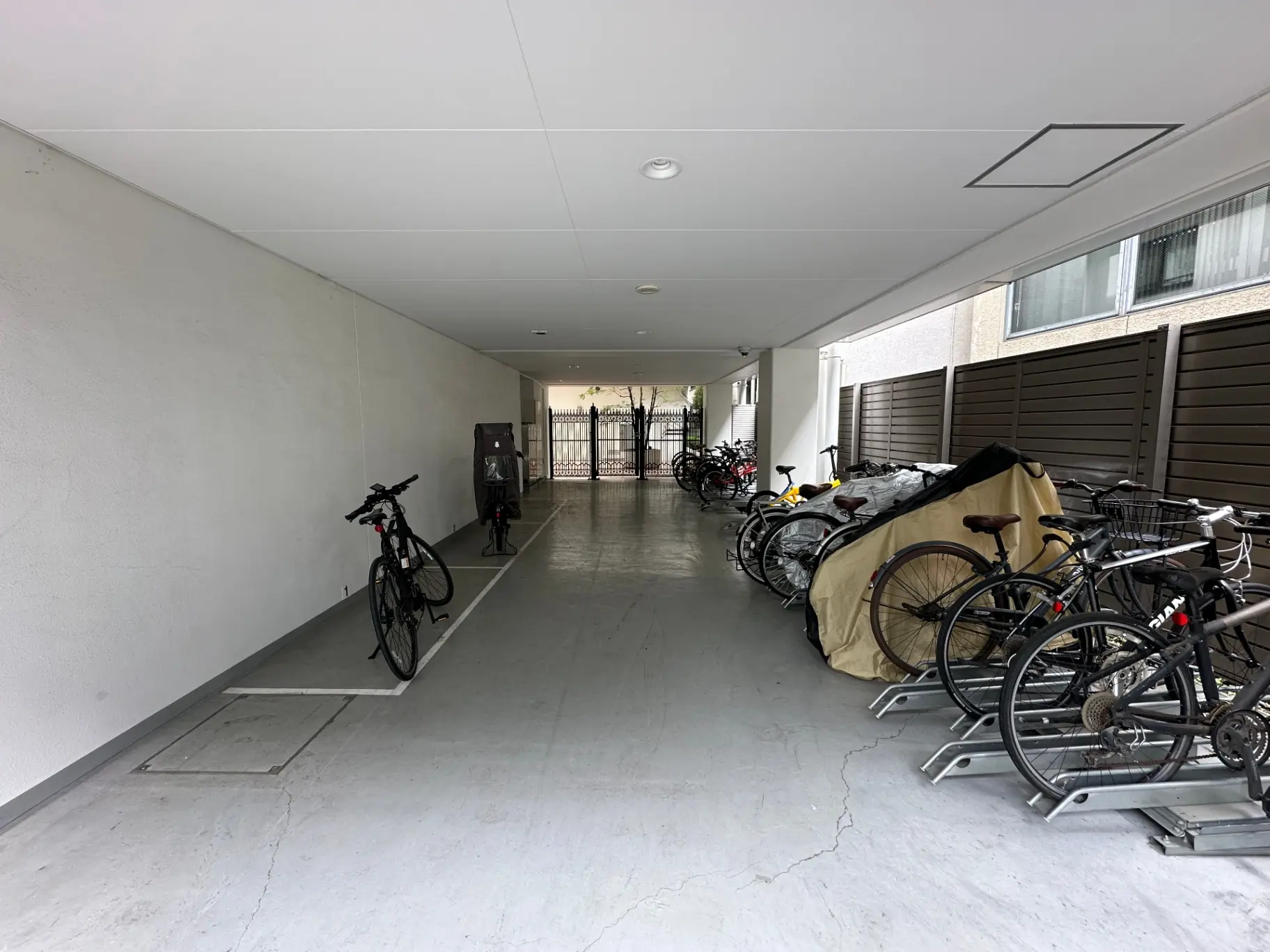 屋根付きの駐輪スペース、バイクラックに並ぶ様々な自転車、シンプルな白い壁と床