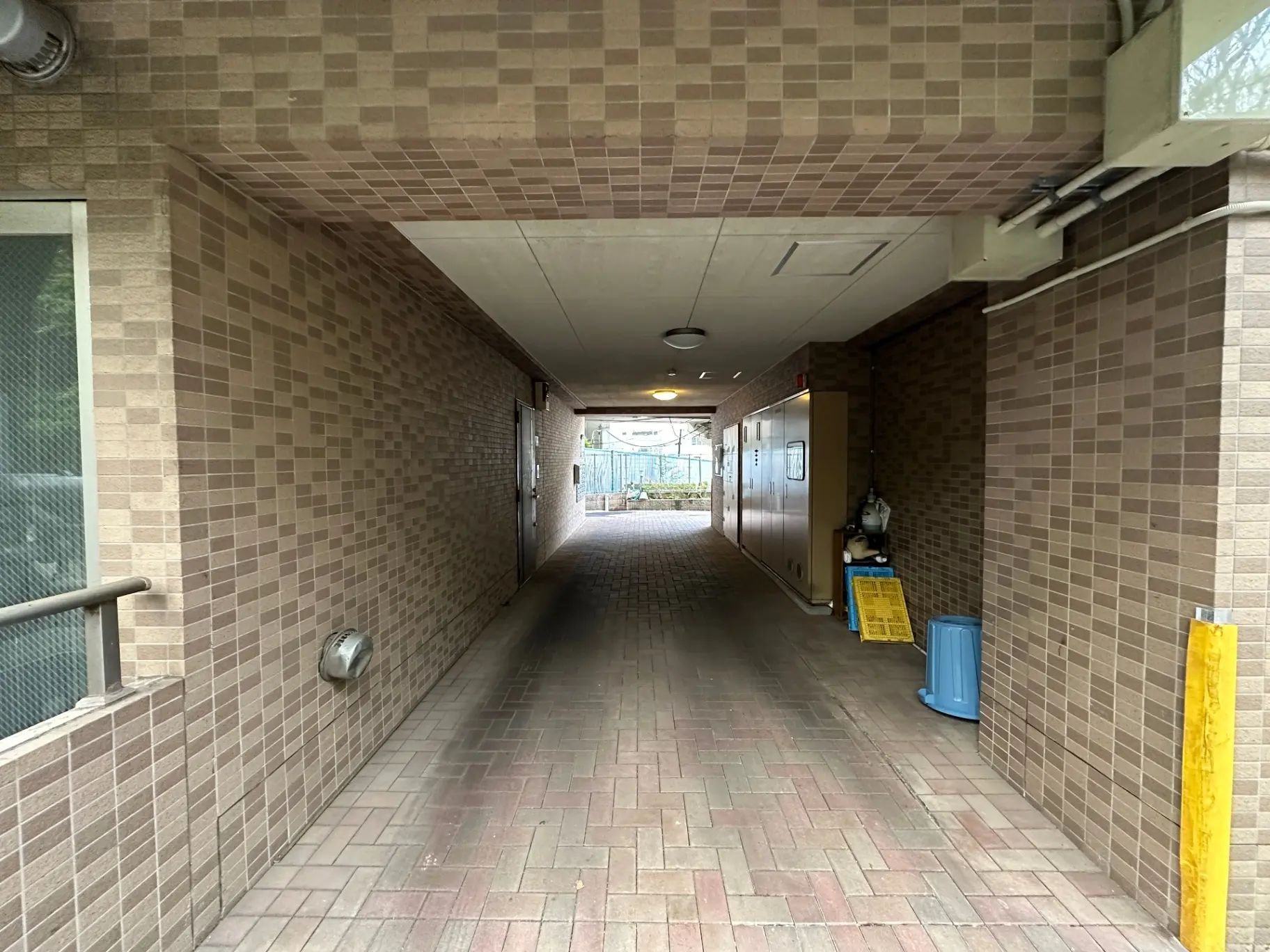 都市のアパートの屋外パスウェイ、茶色のタイル壁と床、天井に照明設備