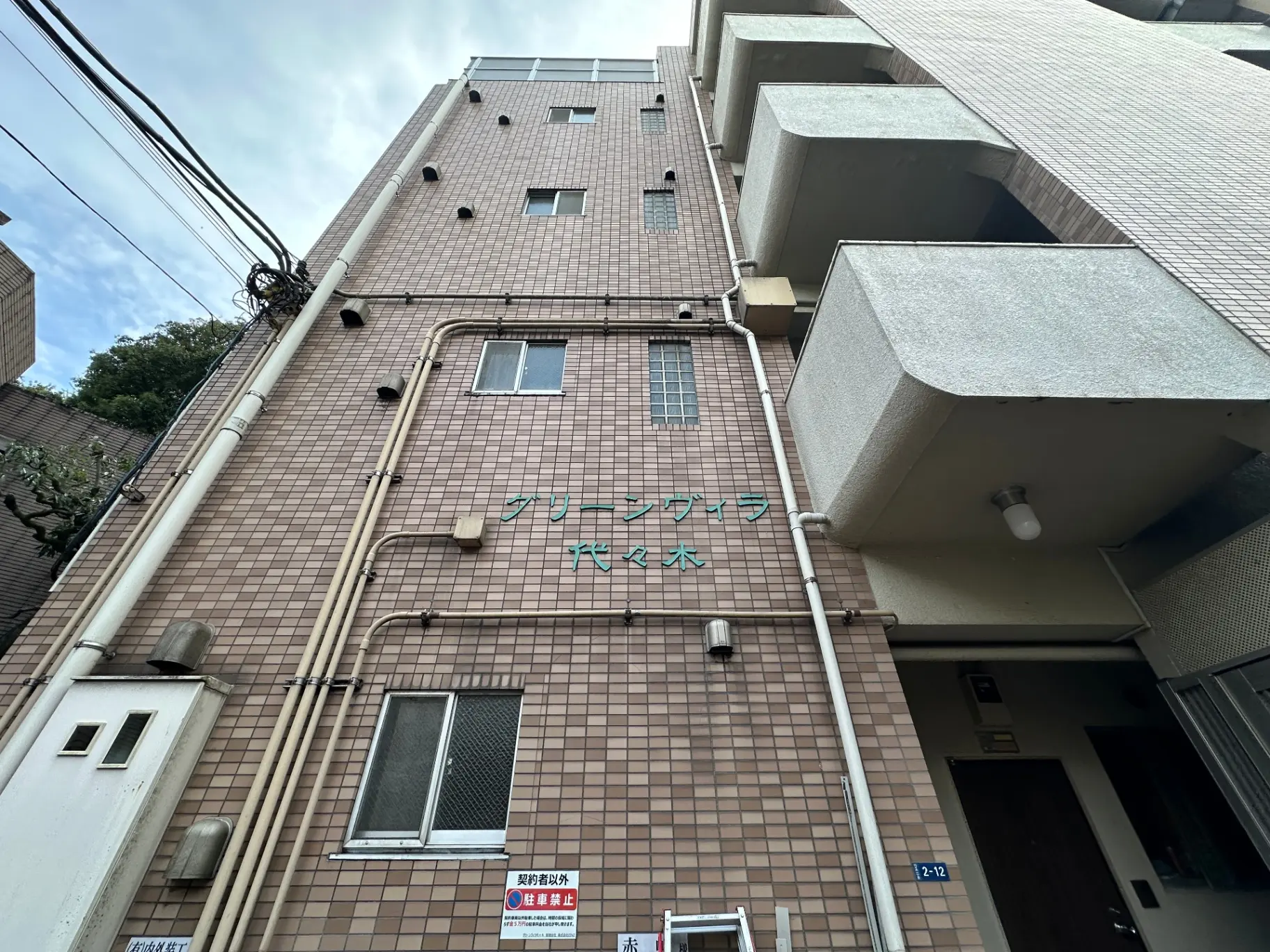 日本の都市部にあるアパートの外観、タイル張りの壁とバルコニーが特徴の多階建てビル