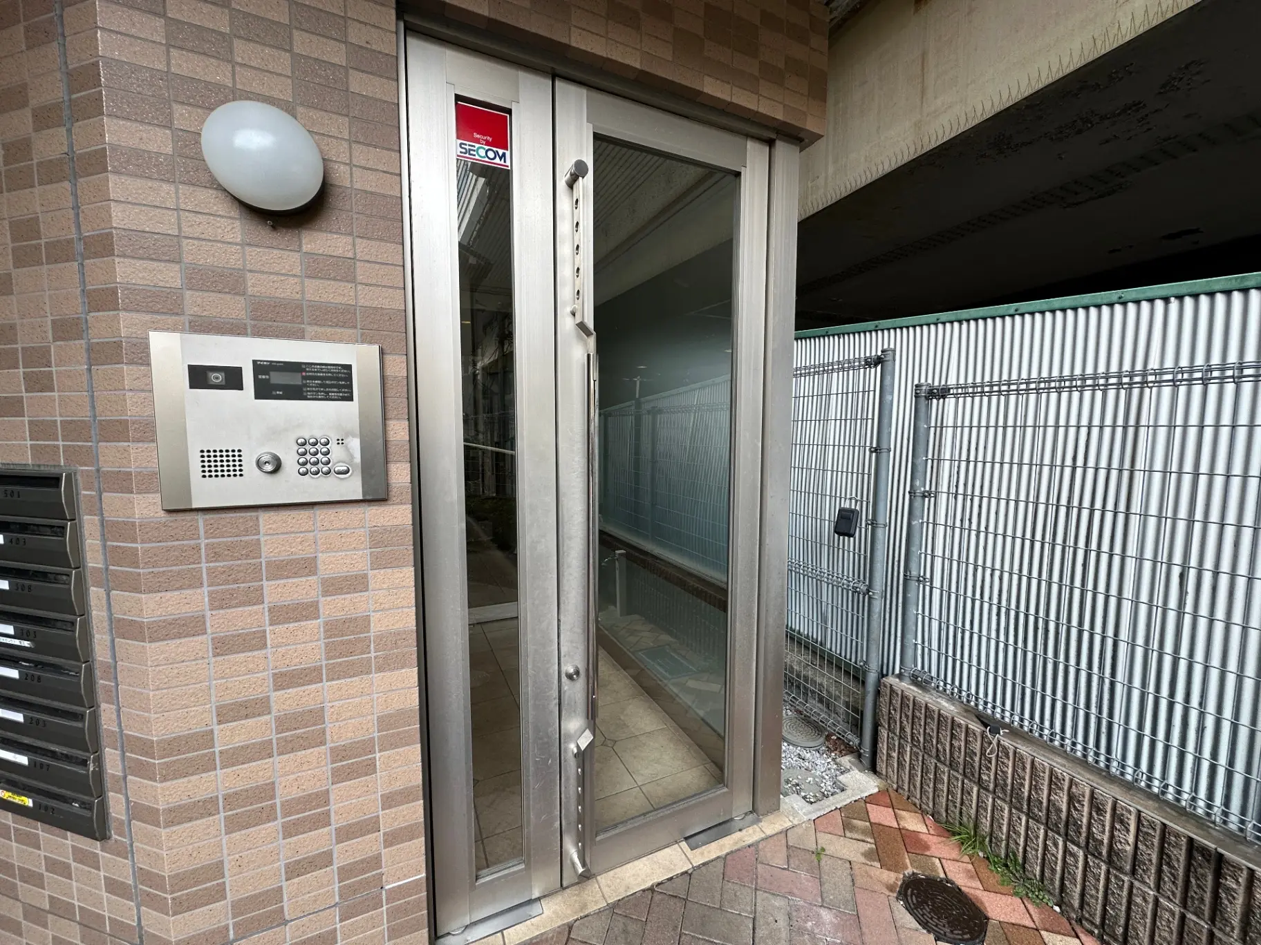 安全性を考慮したマンションのエントランス、インターホンとSECOMの防犯システム、タイル張りの壁