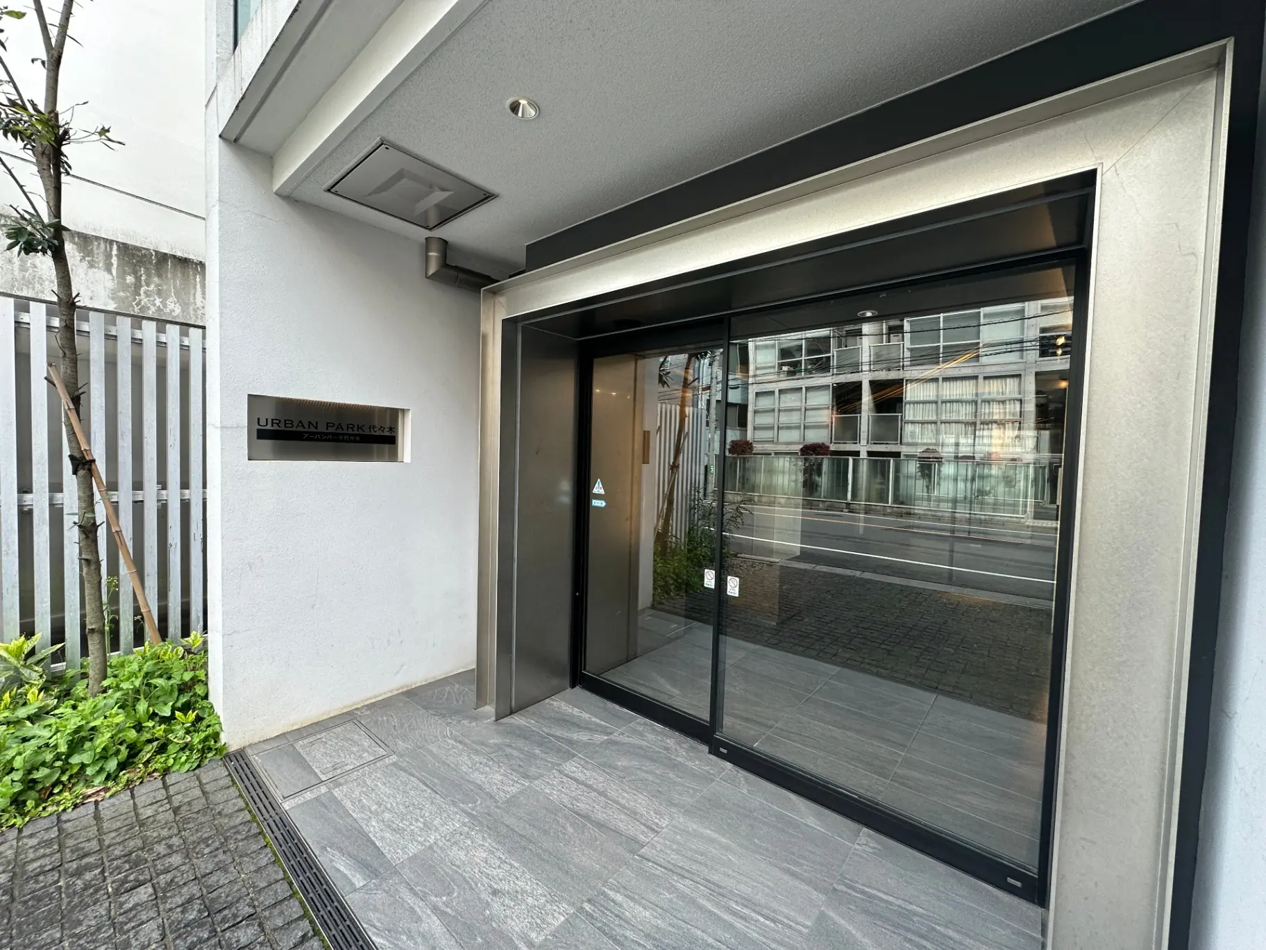 都会的なデザインのアーバンパークマンションのエントランス、スライドガラスドアとモダンな外観