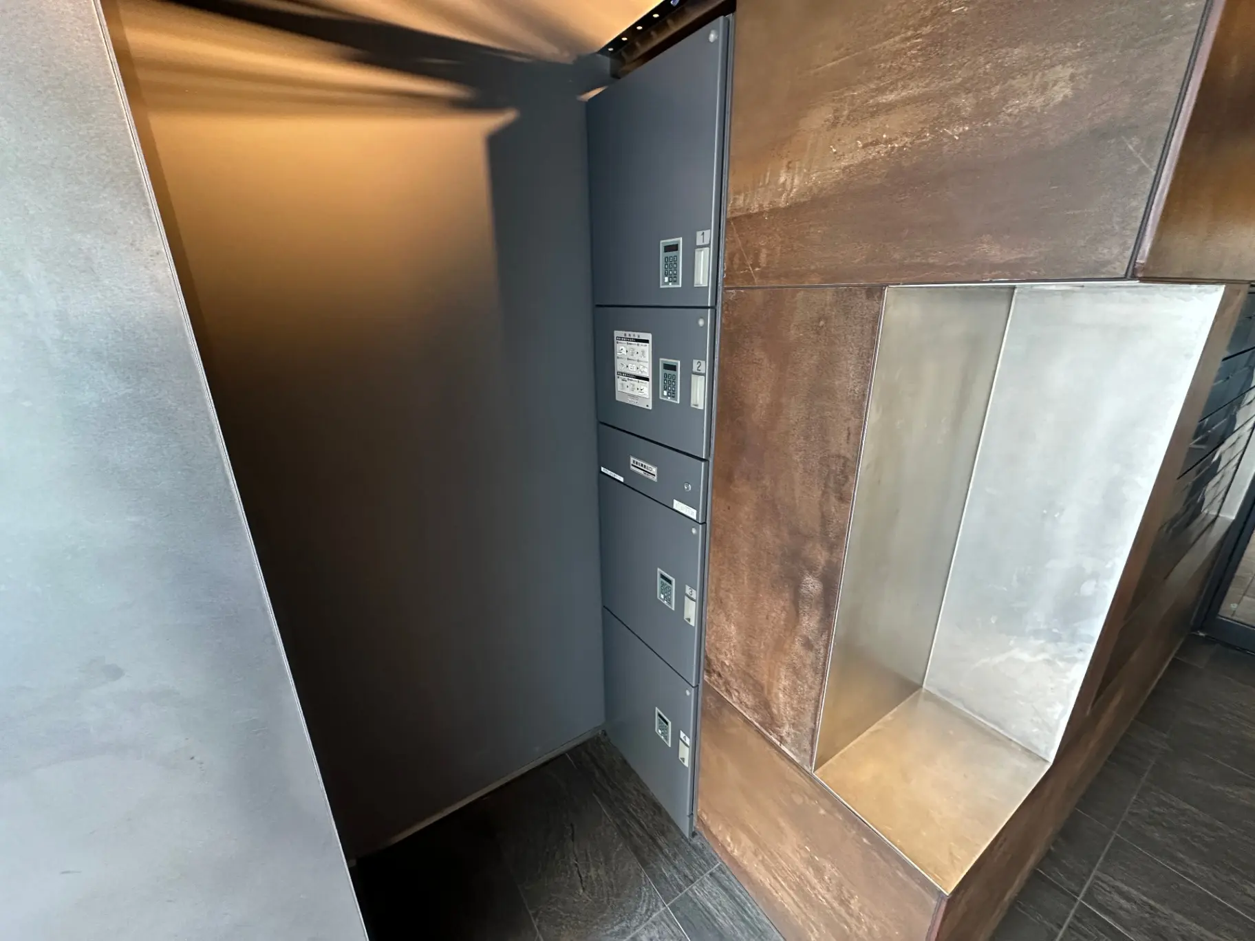 モダンなエントランスホール、ダークグレーの壁にポスト、木製と銀色の内装デザイン