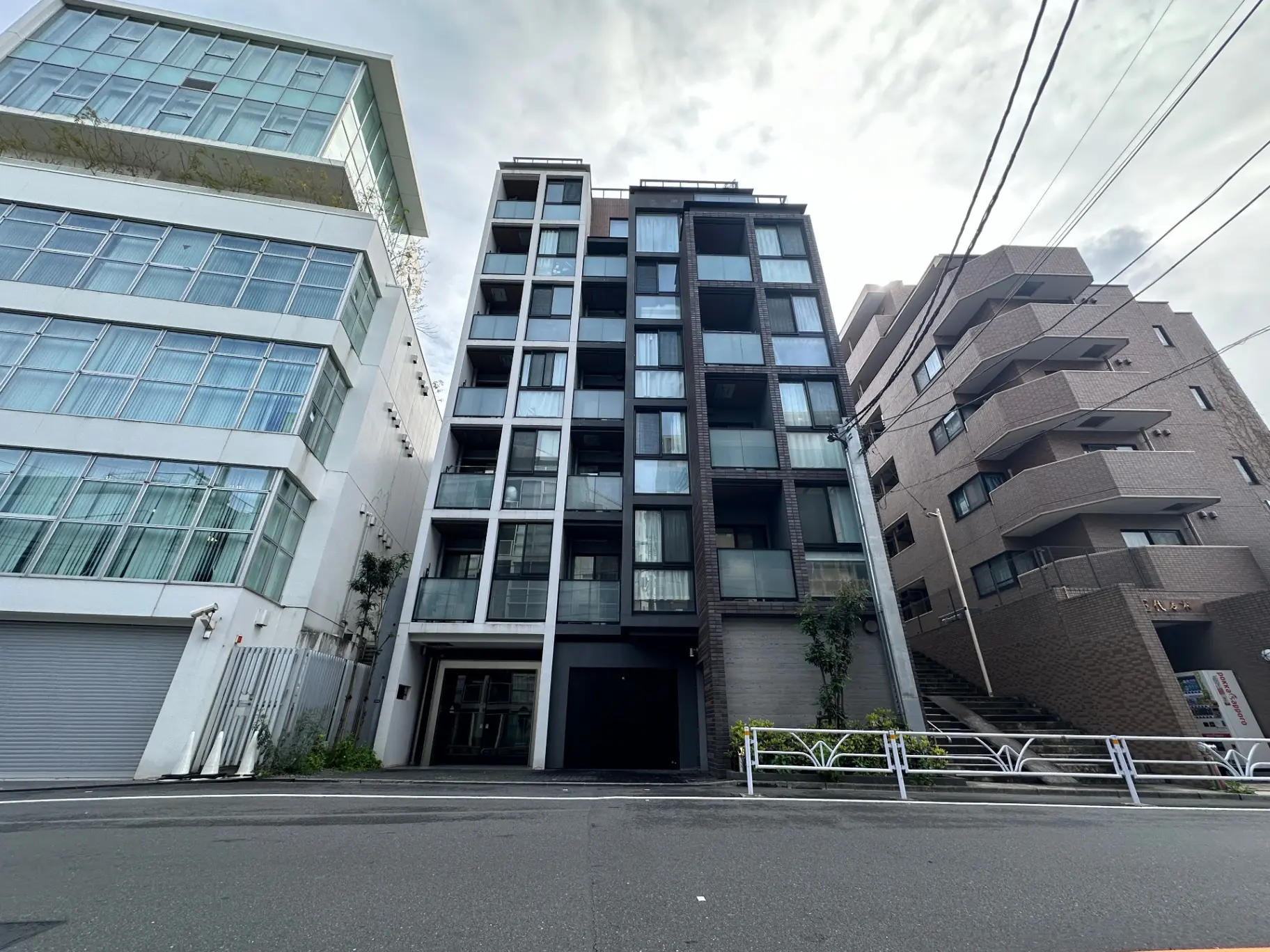 現代的なデザインのマンション外観、街路沿いに建つ複数の建物の景色