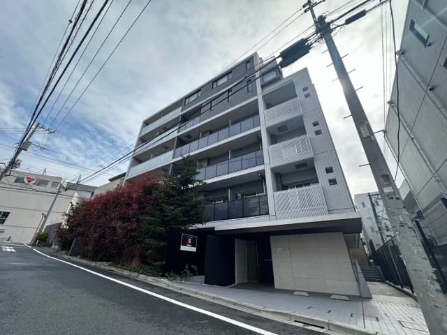 都市の中でモダンなマンションの外観、青空と電線が交差する景色