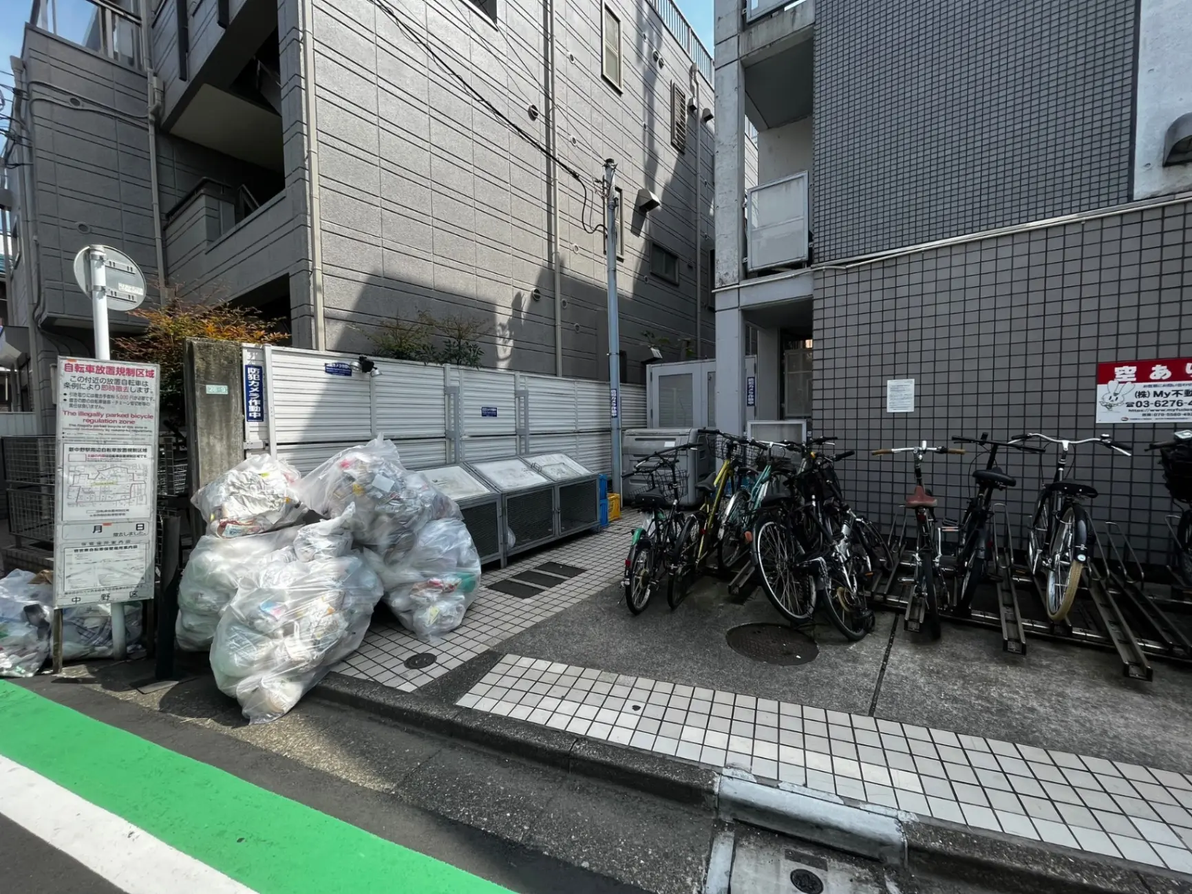 都市部のアパートのゴミ収集エリアと自転車駐輪スペース、整理された分別ゴミと並べられた自転車
