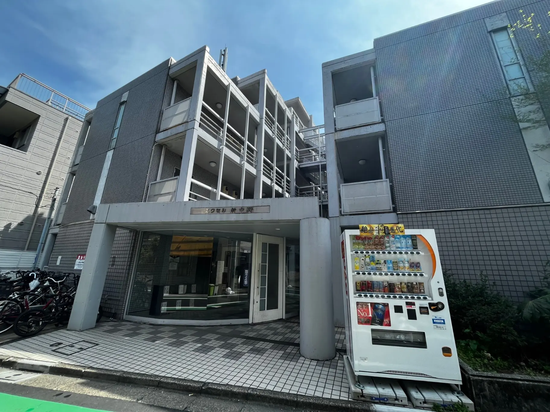 都会のマンションのエントランス、自動販売機が設置されている外観