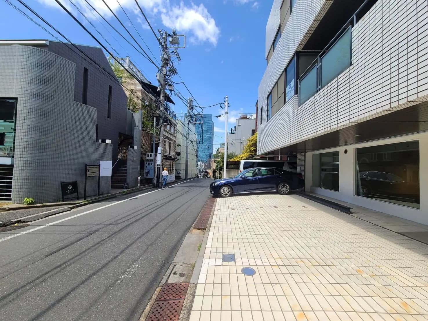 現代的な建築スタイルの都会的な街並み、晴天の下での青空と電線が交差する景色