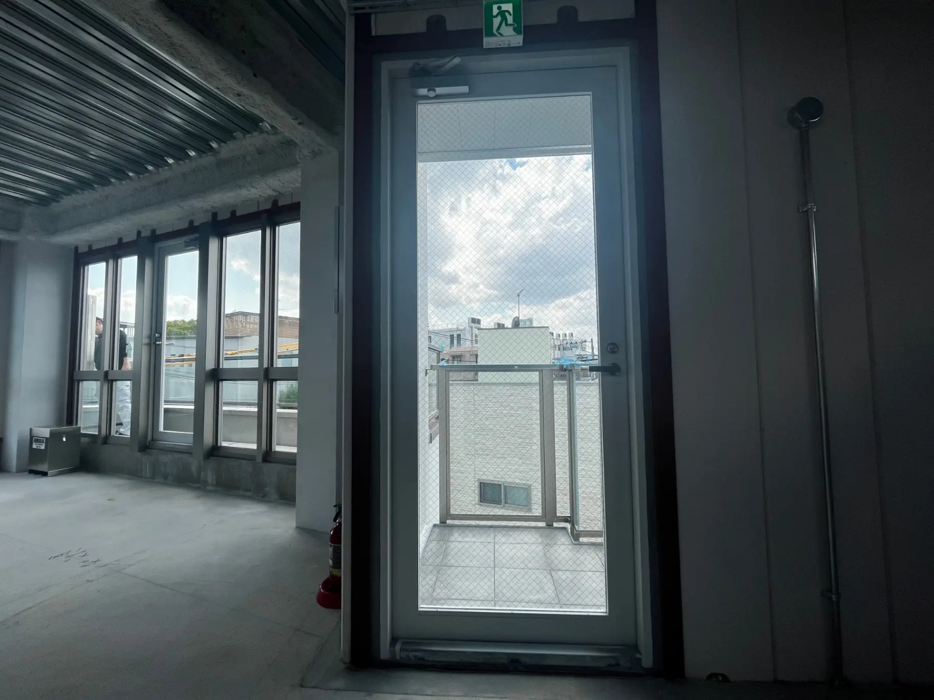 未完成のオフィス空間、コンクリートの床と天井、大きな窓からの自然光、建設途中の内装