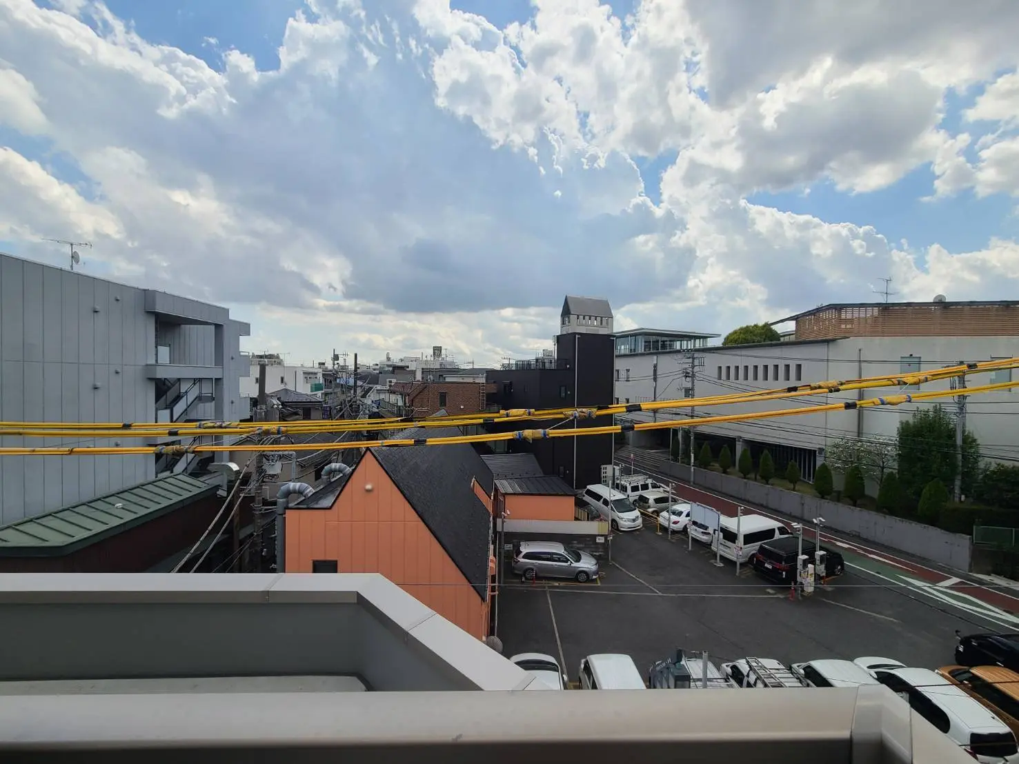 市街地の景観、建物の屋上、クリアな空と雲、駐車場と車