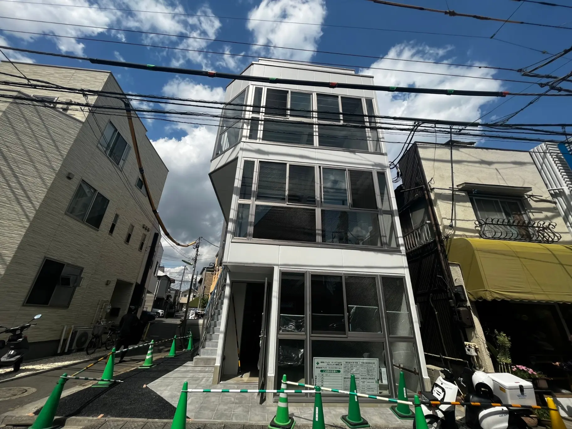 現代的なデザインのビル、ガラス張りの窓、電線と周囲の建物が見える都市の風景