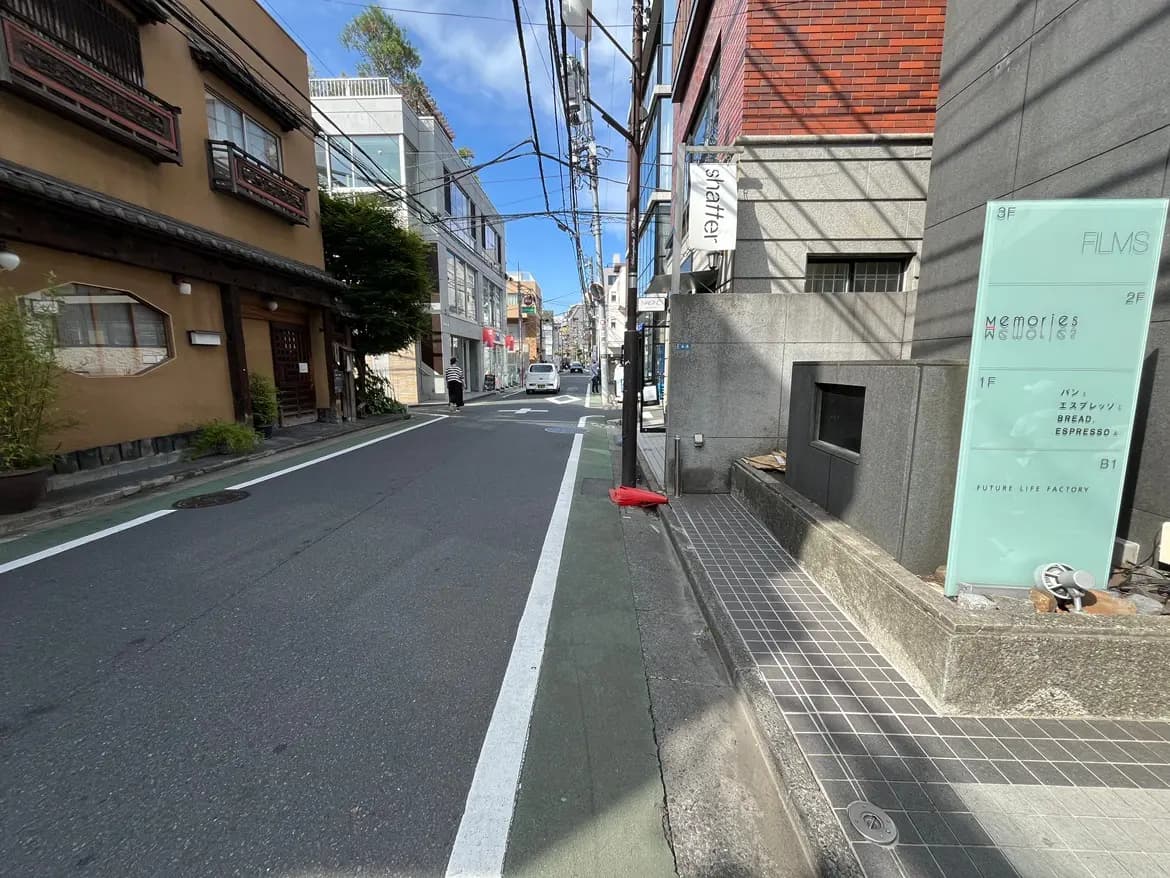- 街並みの風景、伝統的な日本家屋と現代的な建物が並ぶ通り、青空と電柱が映えるシーン