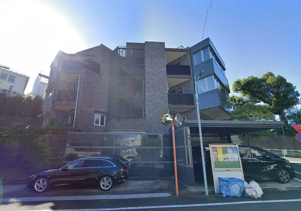 都会的なデザインのマンション外観、高級車が停車している住宅街の風景