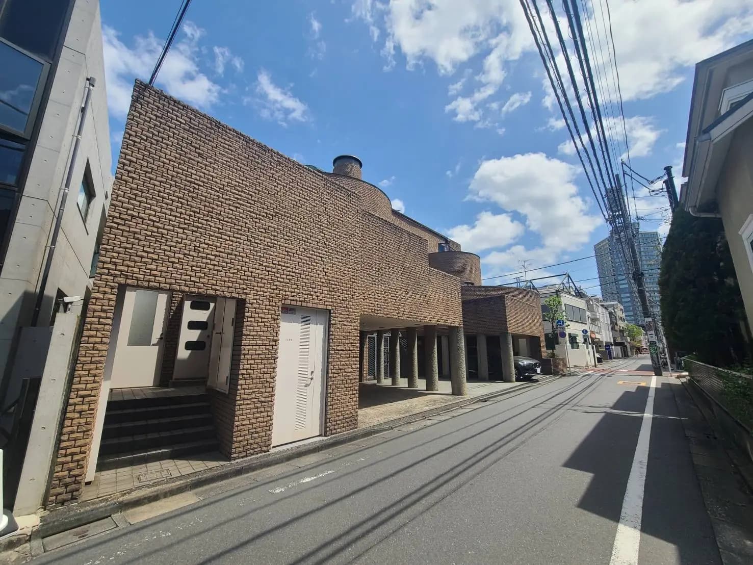 都会的な通りに建つユニークなレンガ造りの建物、青空と電線が交差する景観