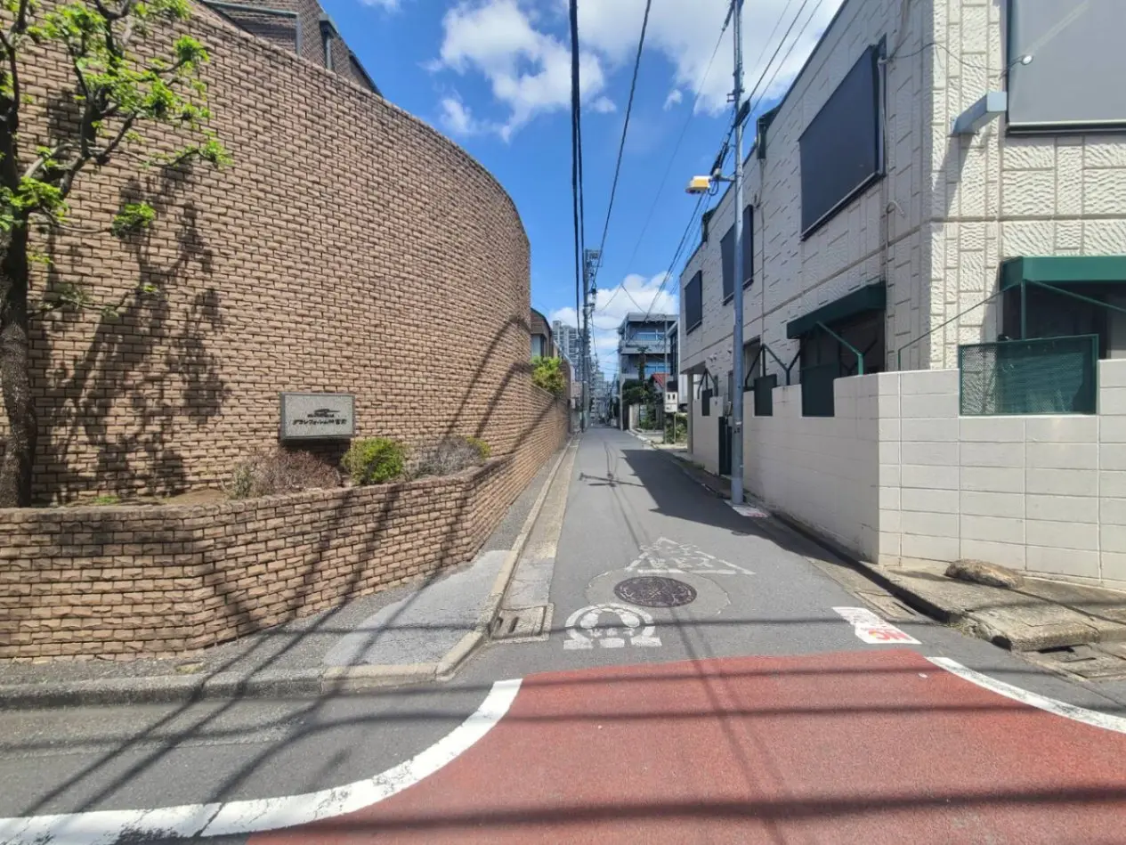 青空の下、レンガ造りの壁とアーチ型木造の看板のある静かな道路