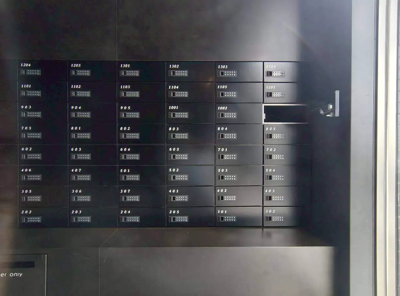 - ブラックのダイヤル式ロッカーが整然と並んだ集合住宅の郵便受けボックス、異なる番号が表示された収納スペース