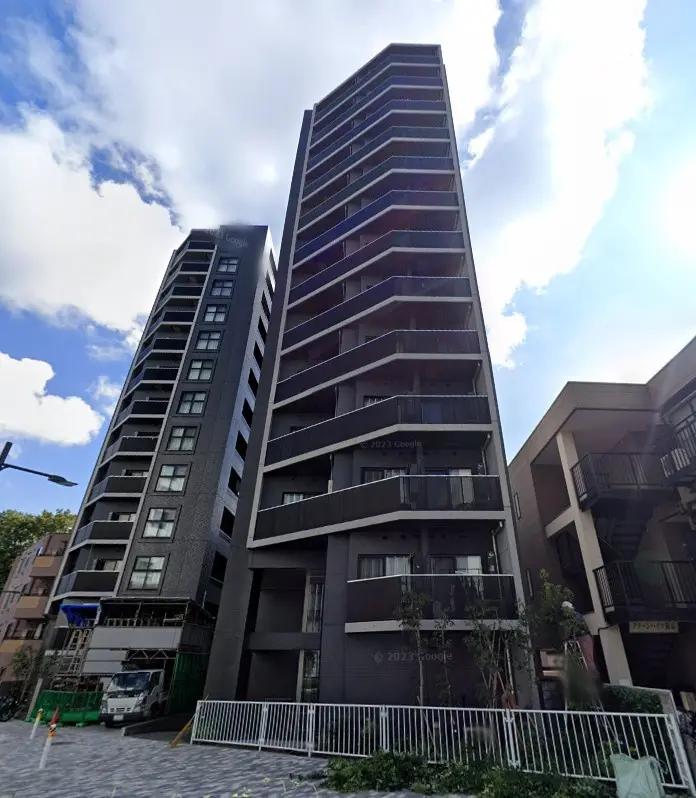 現代的なデザインの高層マンション、都会の住宅街に立つ建物、青空と緑の植栽が映える外観