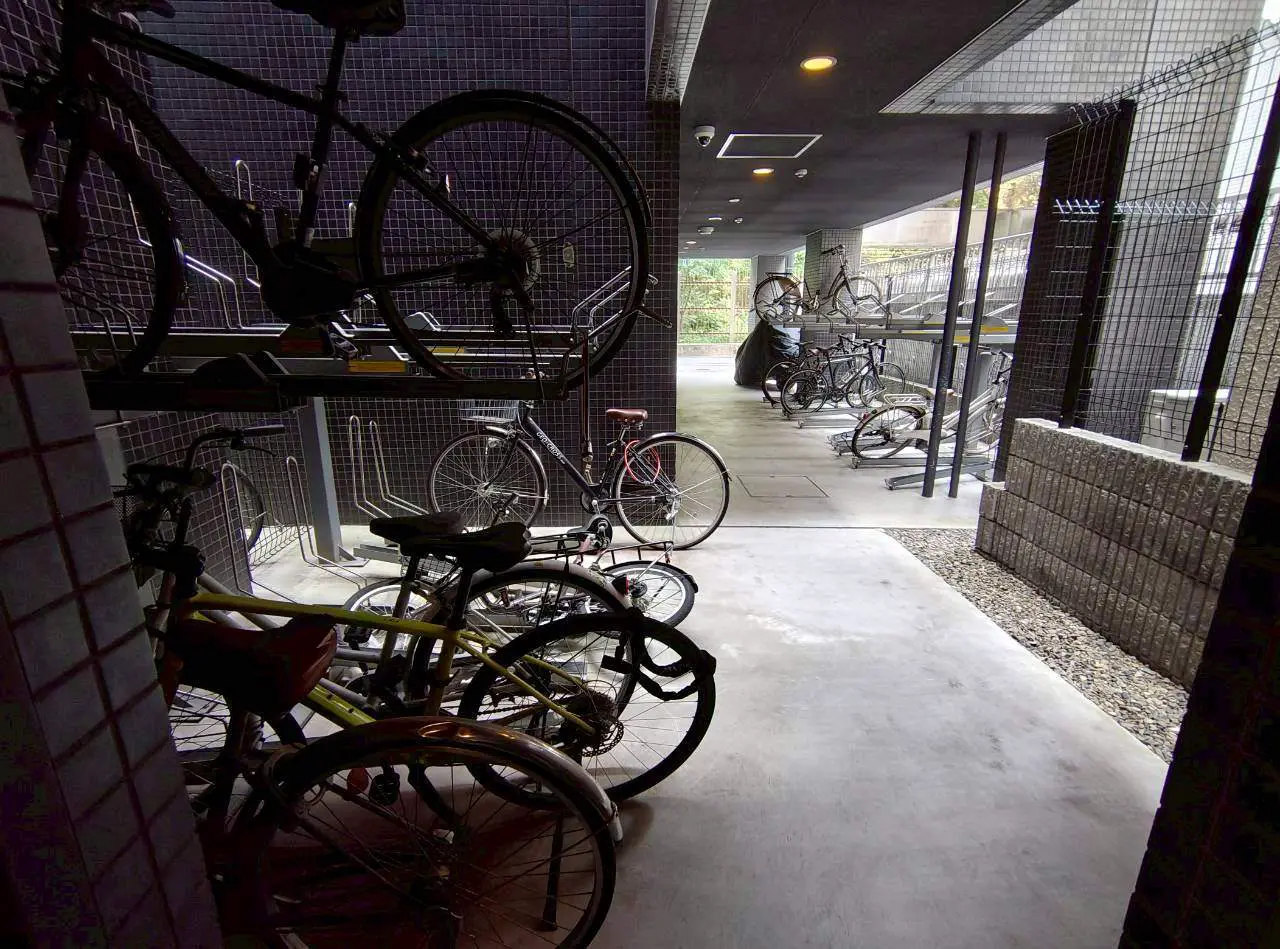 - 自転車が多数並ぶ屋内のバイク置き場、二段式ラックと開放的な通路のあるデザイン
