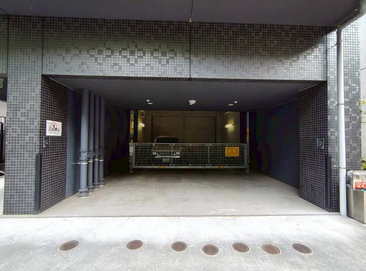 - モダンなデザインの地下駐車場、鉄製のゲートと照明があり、壁はコンクリート仕上げのインテリア