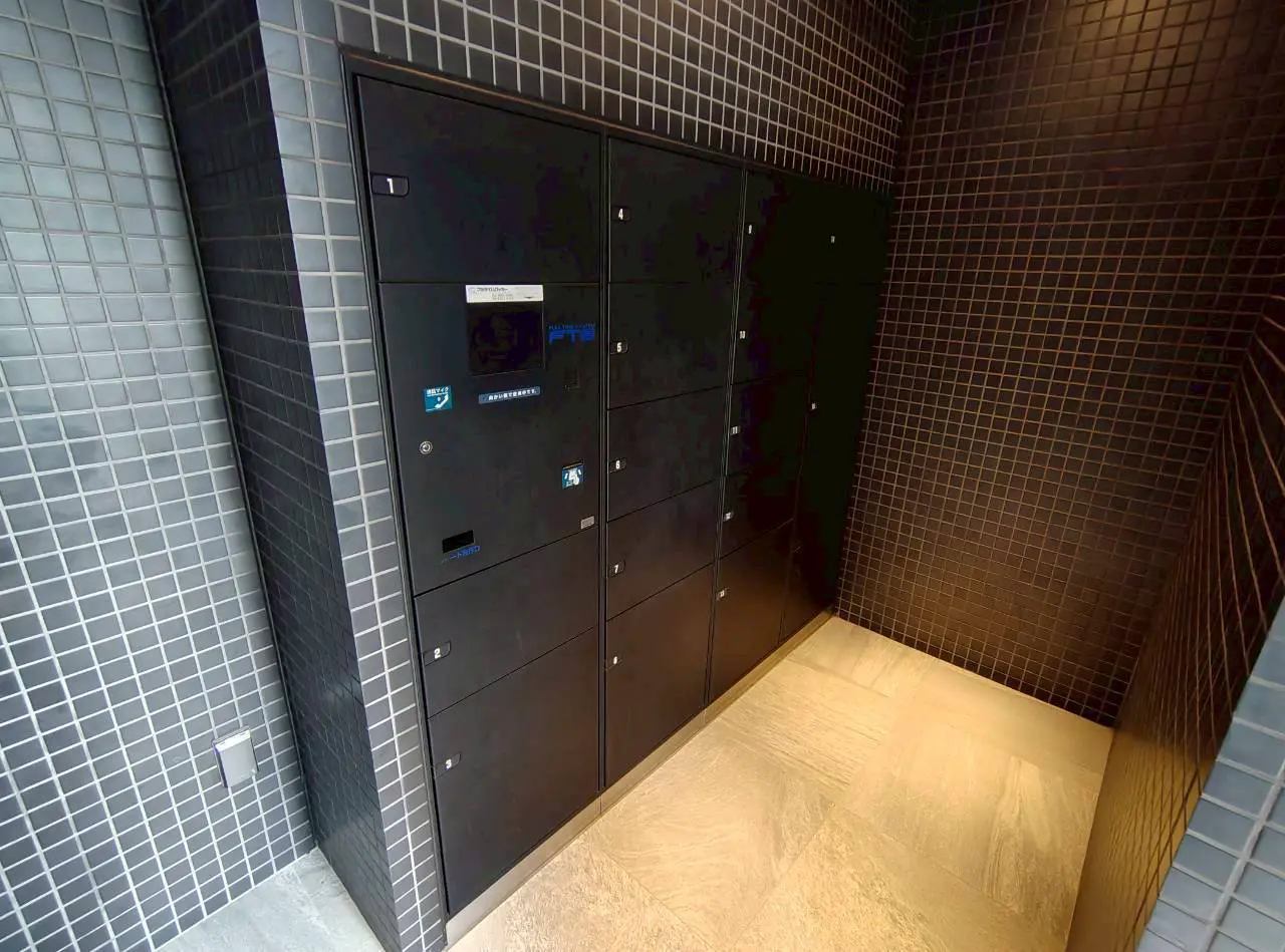 - モダンなデザインの宅配ボックス、黒いタイルで囲まれたエリア、清潔感のある収納スペース