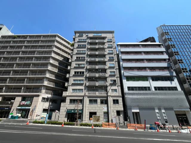 - 都市の高層ビル群、異なるデザインの建物が並ぶ様子、青空の下での賑やかな街並み