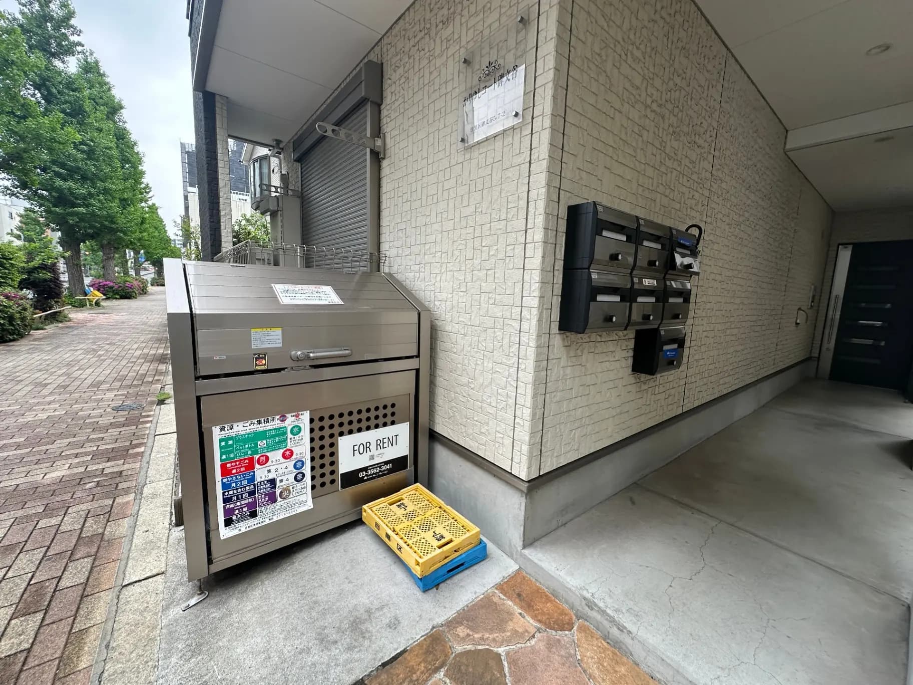 マンションのエントランスにある宅配ボックスと郵便受け、貸し出し中と表示された看板がある外観