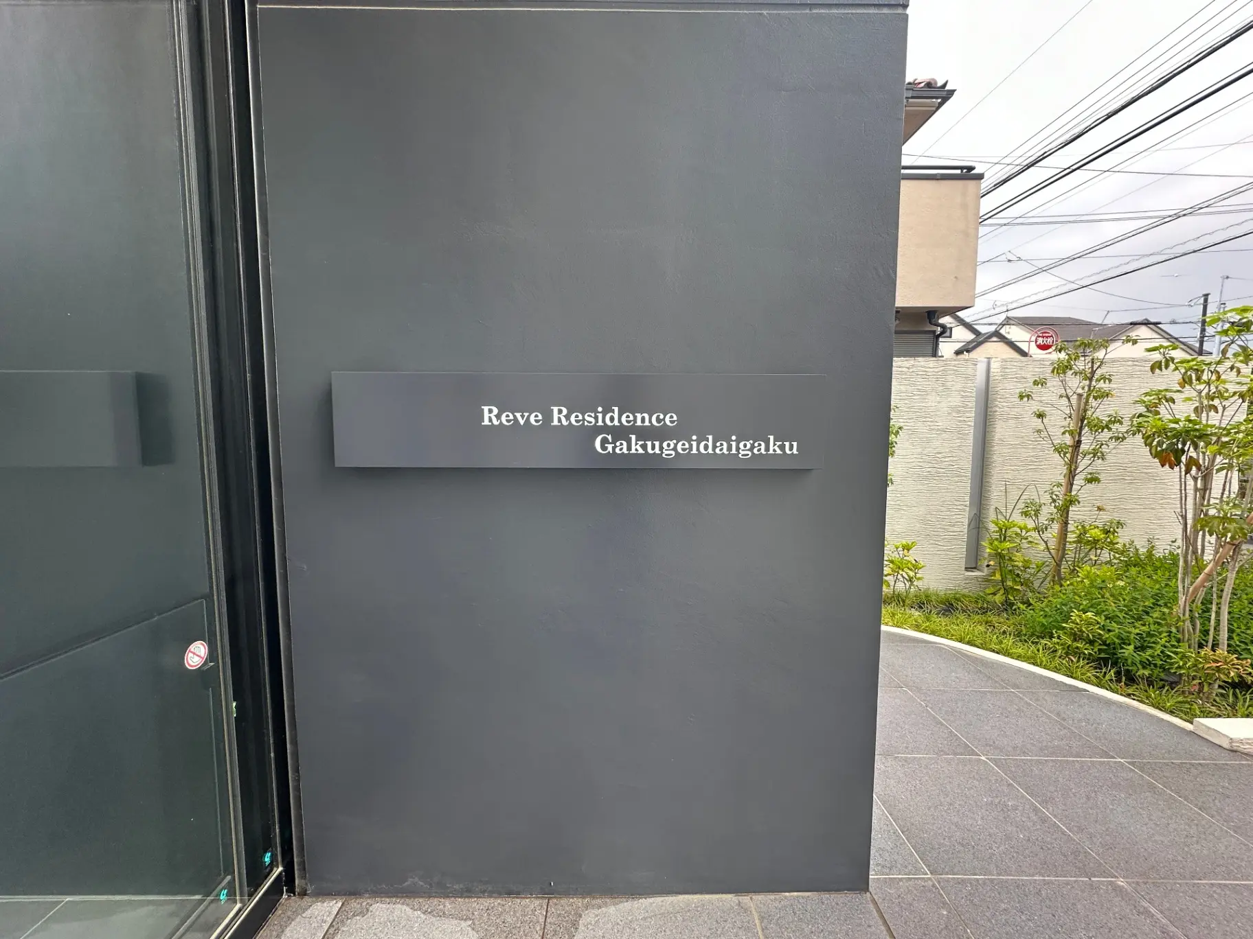 高級感ある外観のReve Residence Gakugeidaigakuエントランス、上質な仕上がりの黒い壁とプレートサイン