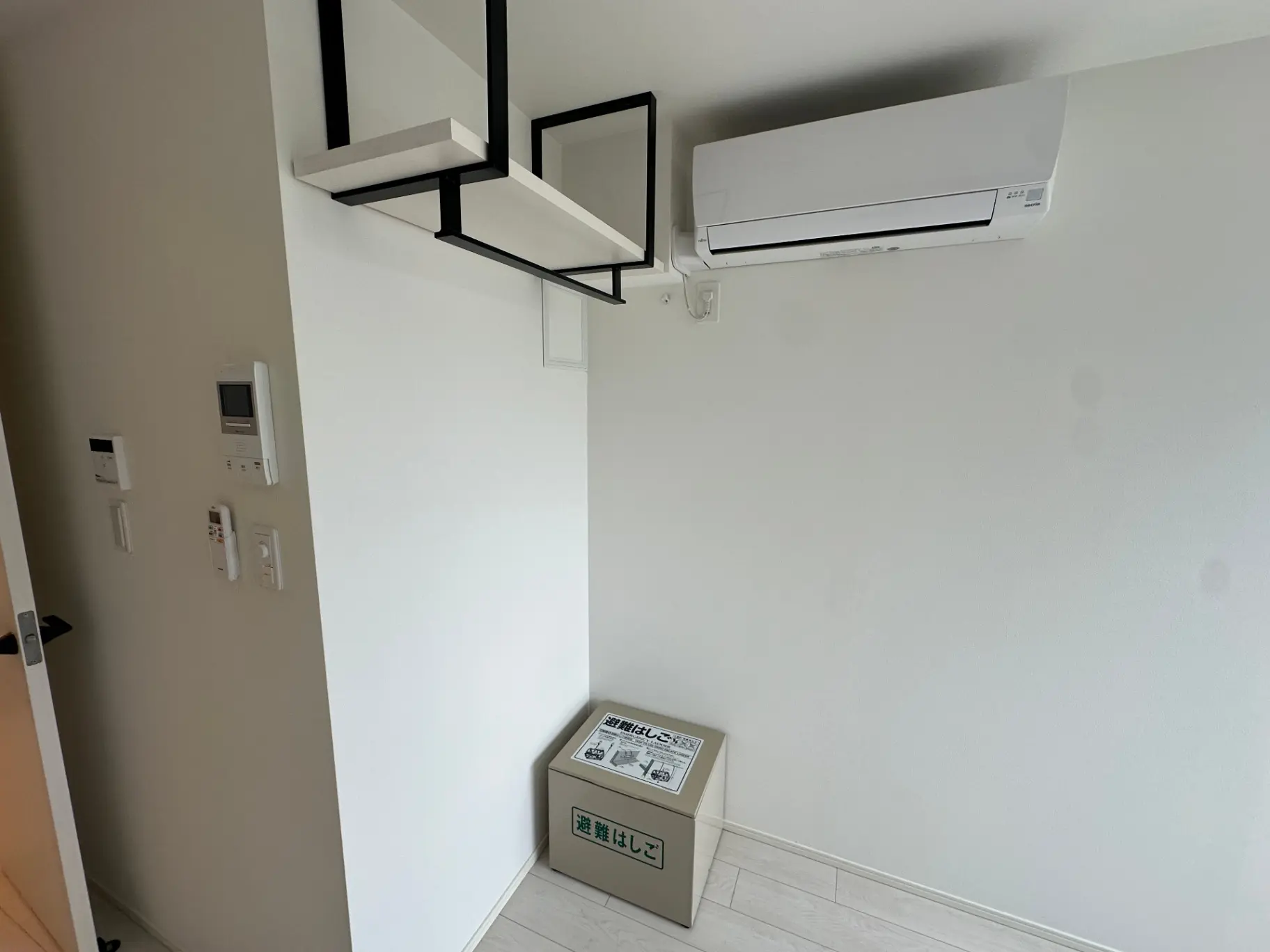 シンプルなデザインの家庭用エアコン、壁掛け式、セキュリティインターフォンと配電盤があるエントランスホール