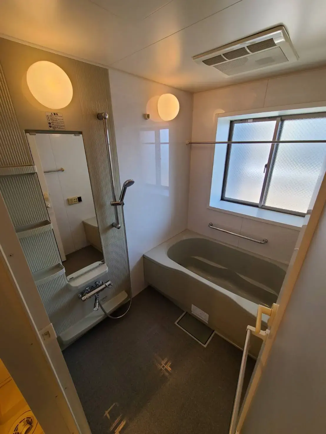 コンパクトなバスルームに一体型バスタブとシャワー、天然光の入る窓