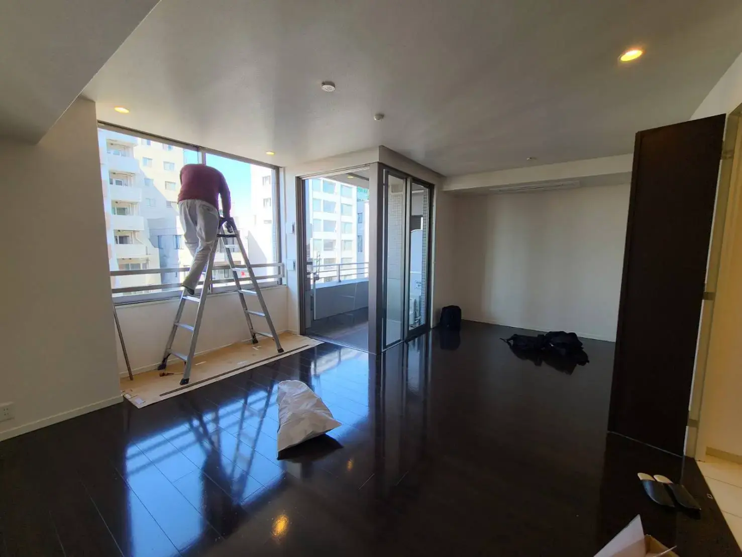 明るい自然光が入るリビングルーム、光沢のある床、バルコニー付き