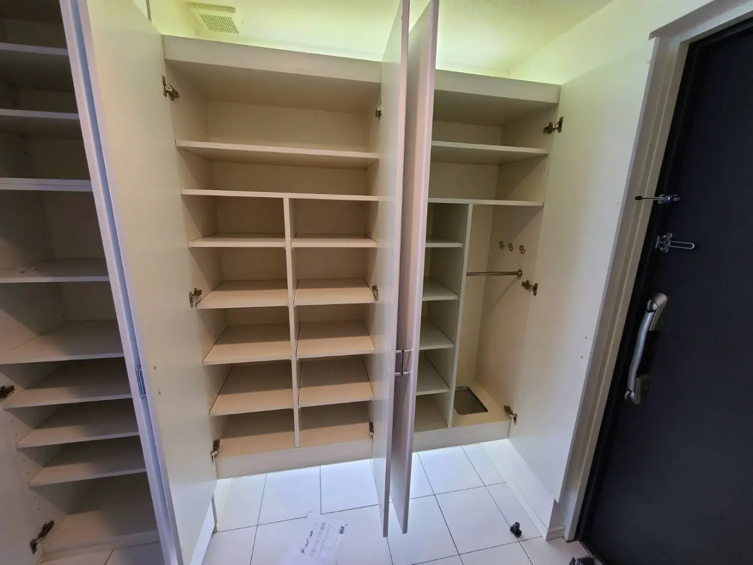 空のクローゼット内部と開いた扉、収納スペースの詳細が確認できる室内の風景