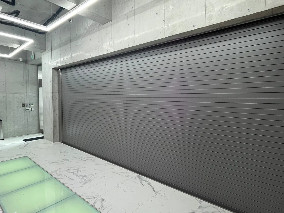 現代的なデザインのガレージシャッター、コンクリートと大理石の床、埋め込み式の照明が特徴的なインテリア