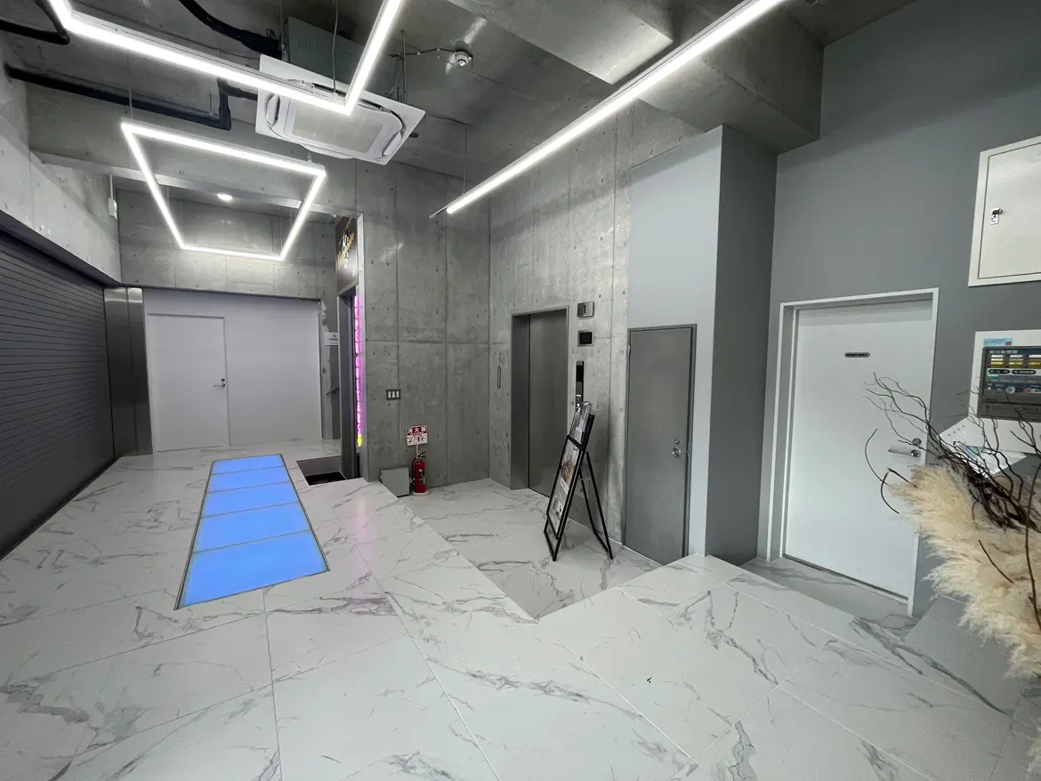 モダンなデザインのオフィスエントランス、洗練されたLED照明、コンクリート製の壁面、大理石調のフロア