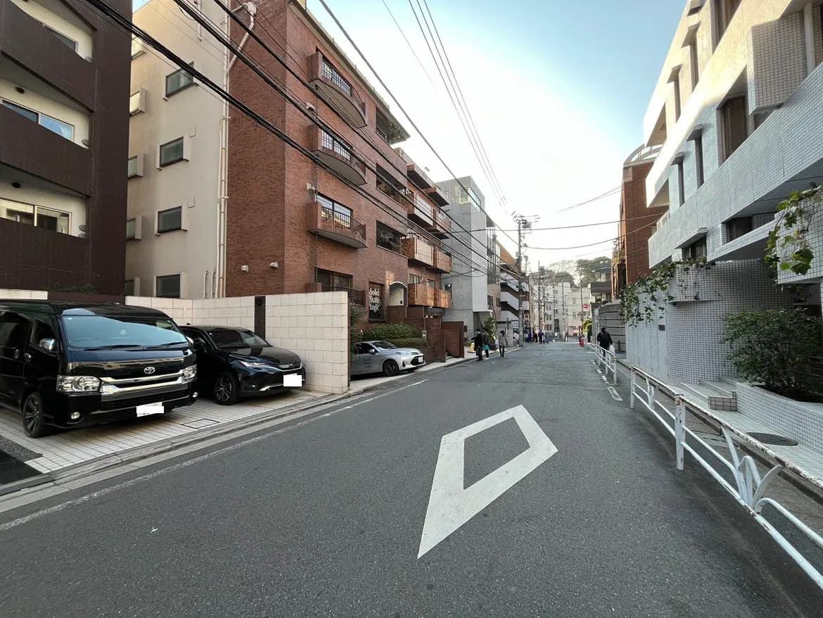 日本の都会の住宅街の通り、マンションと駐車場、歩行者と自然光