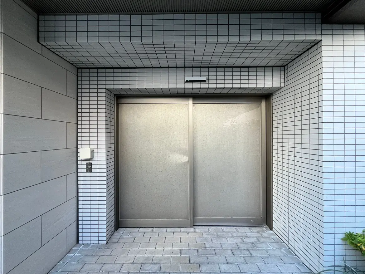 現代的な外観の建物入口、グレーのタイル壁、整然と並んだパターンデザイン